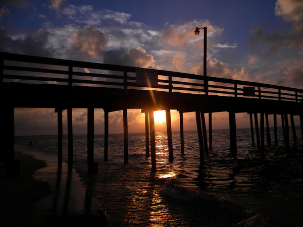 sun setting under the pier